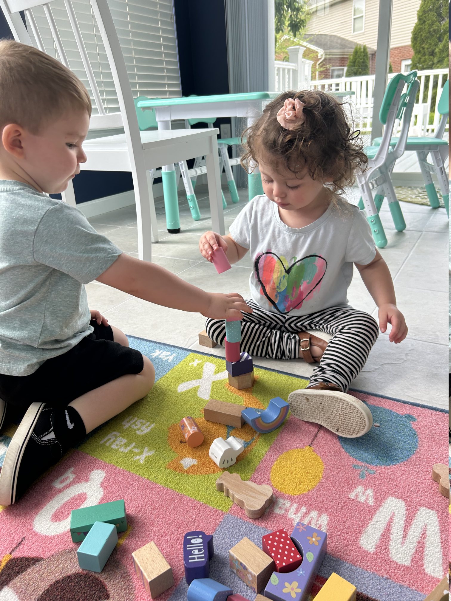 Children playing with wooden blocks on a colorful rug