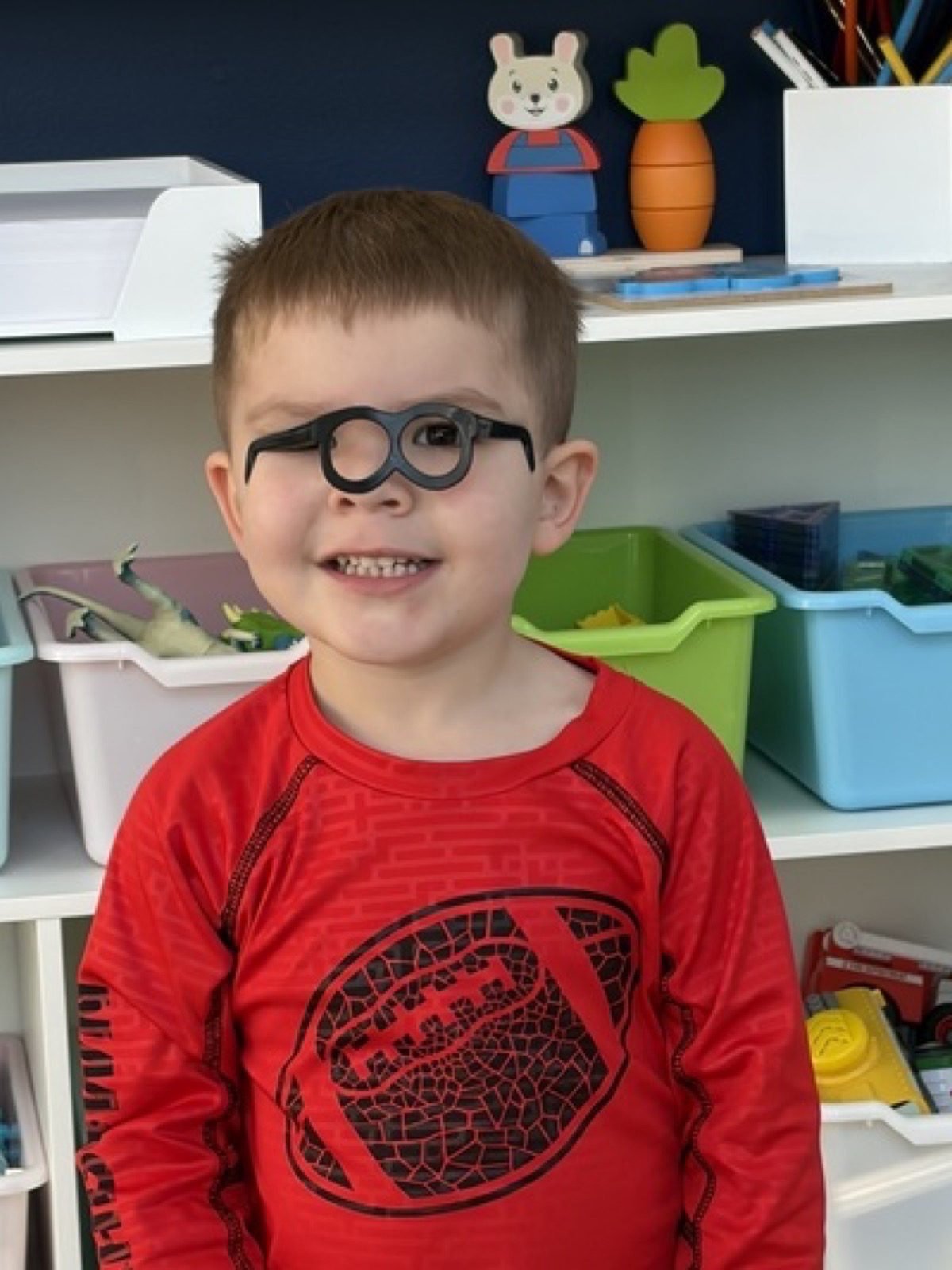 Child smiling while wearing play glasses in the classroom