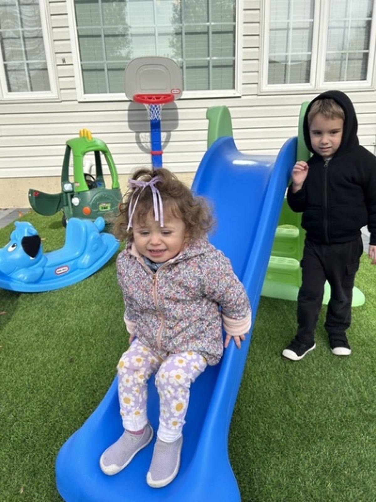 Children playing outside on a blue slide