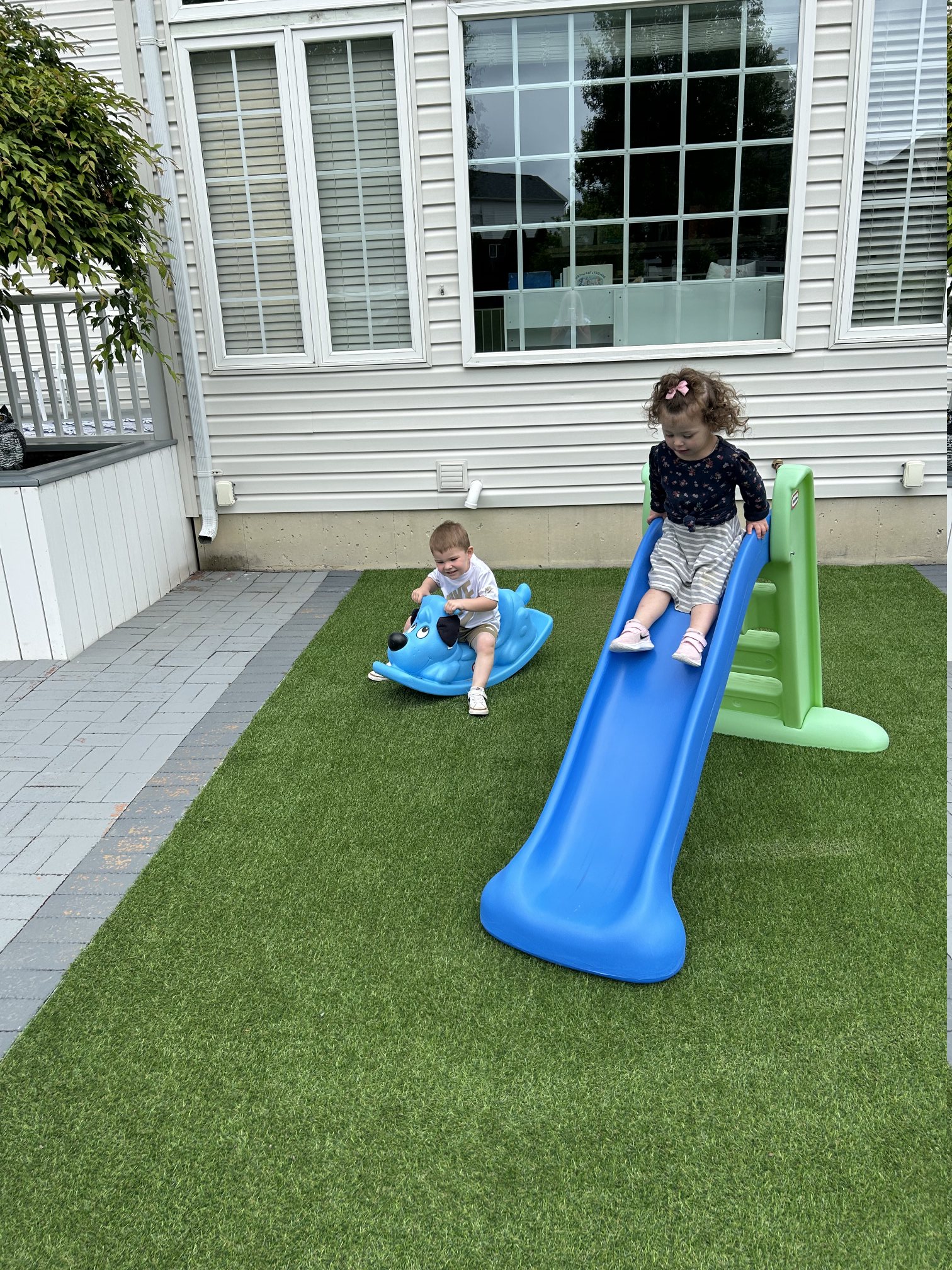 Children enjoying the outdoor play space with slide and rocker toys