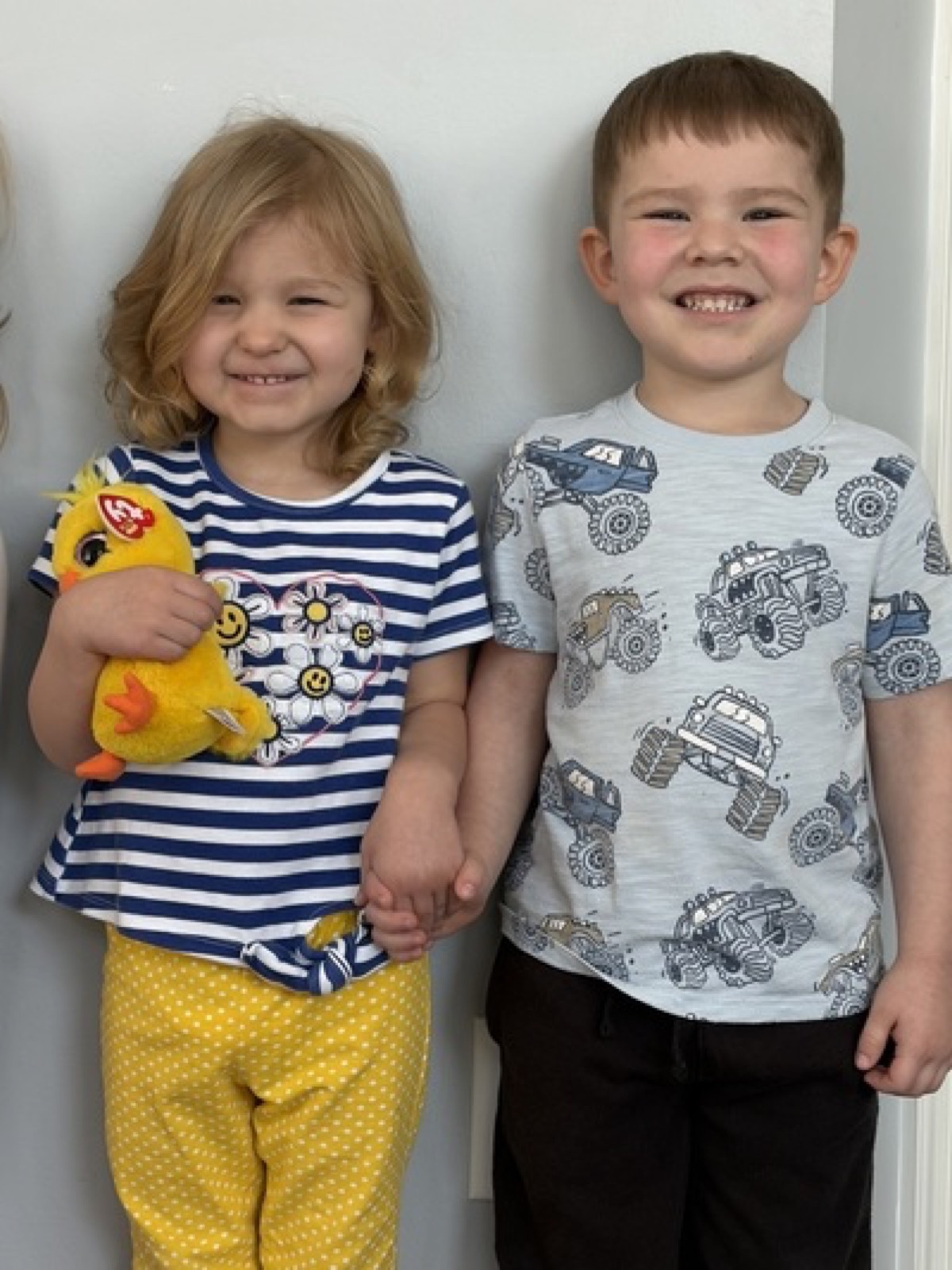 Two children smiling and holding hands