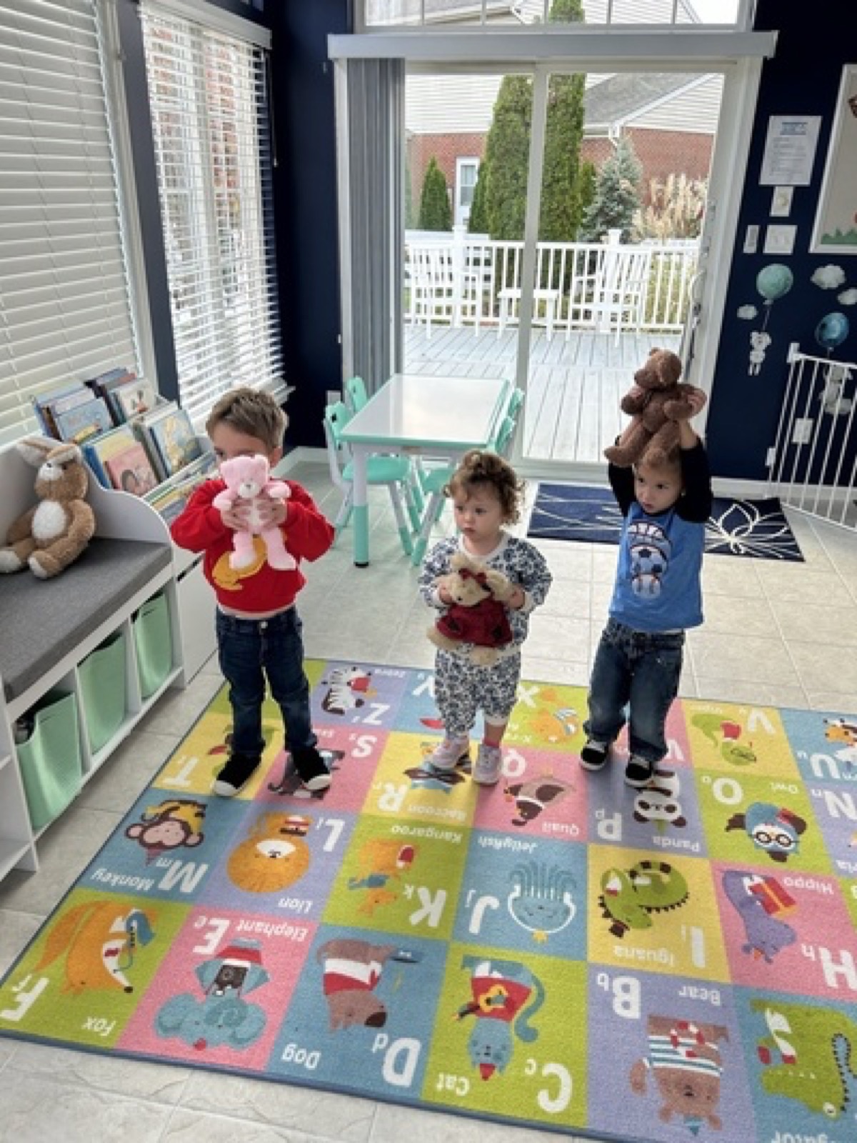 Children standing on a classroom rug holding stuffed animals