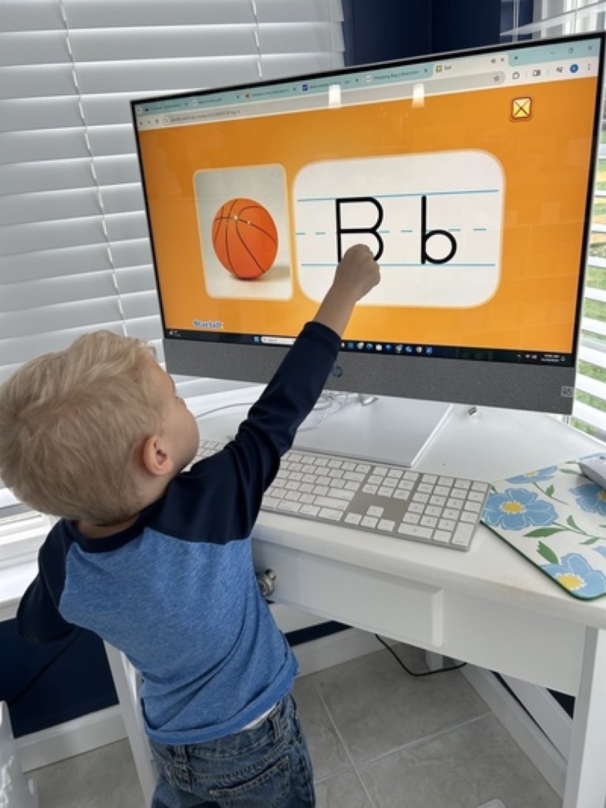 Child practicing a letter activity on a touchscreen