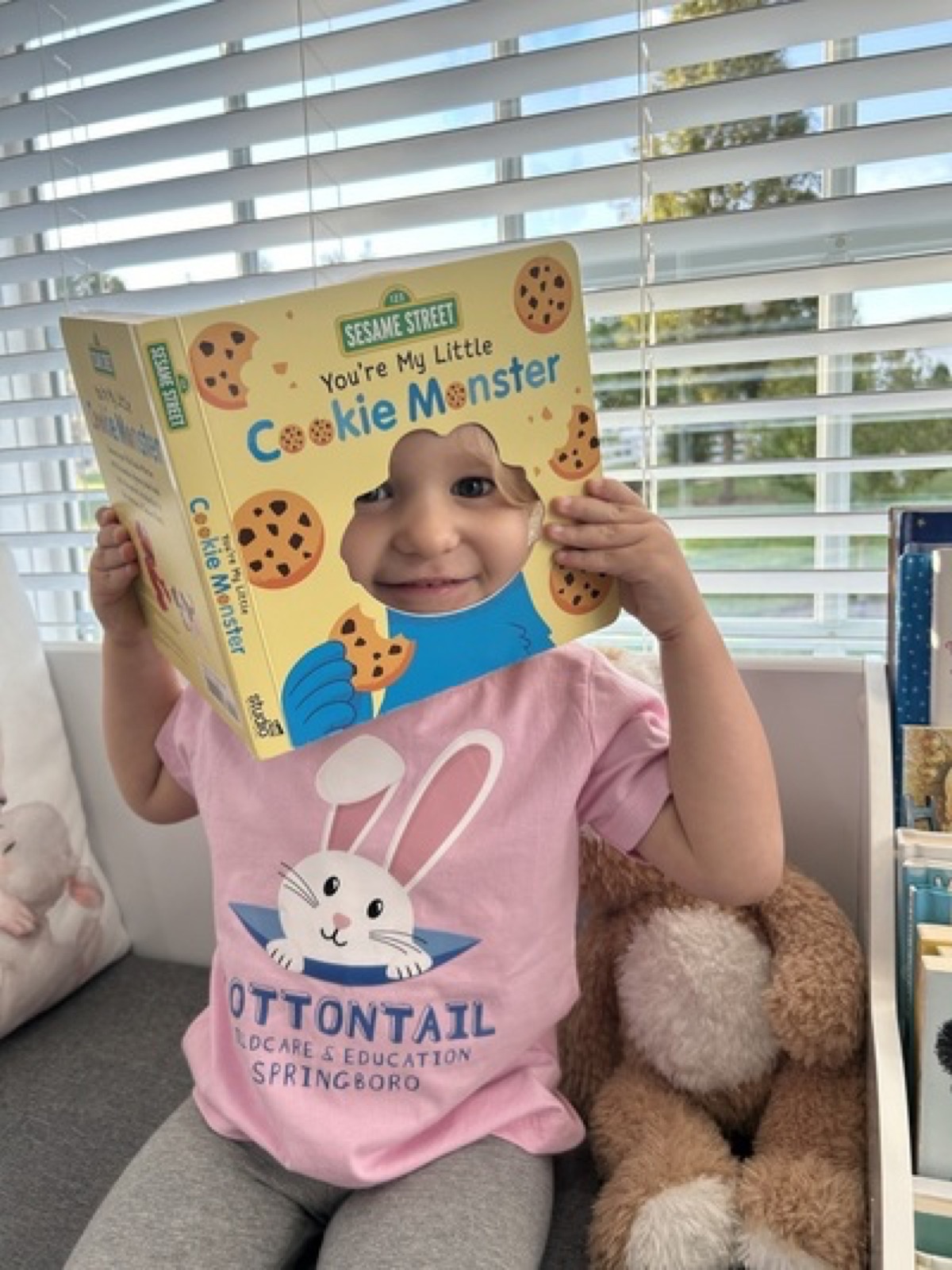 Child holding a Cookie Monster book in the reading area
